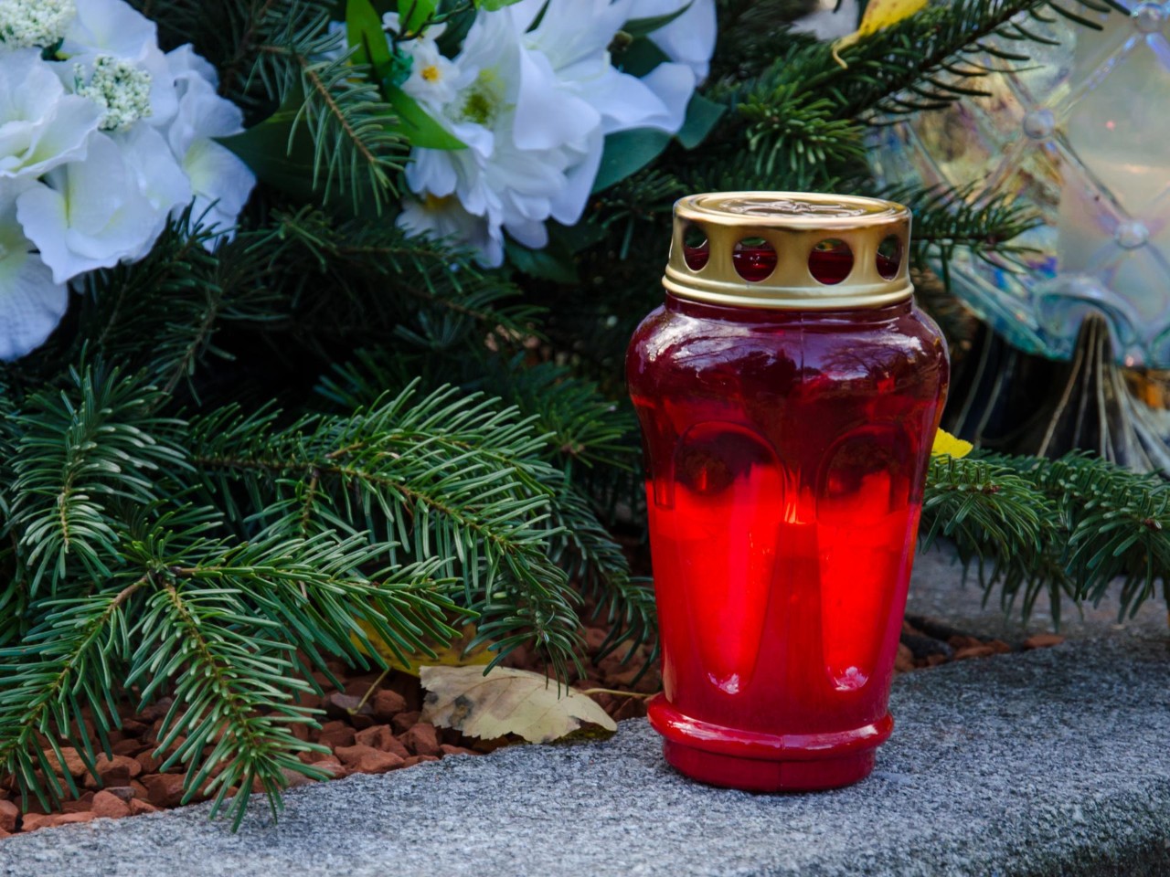 Kerze und Blumenarrangement zu Allerheiligen