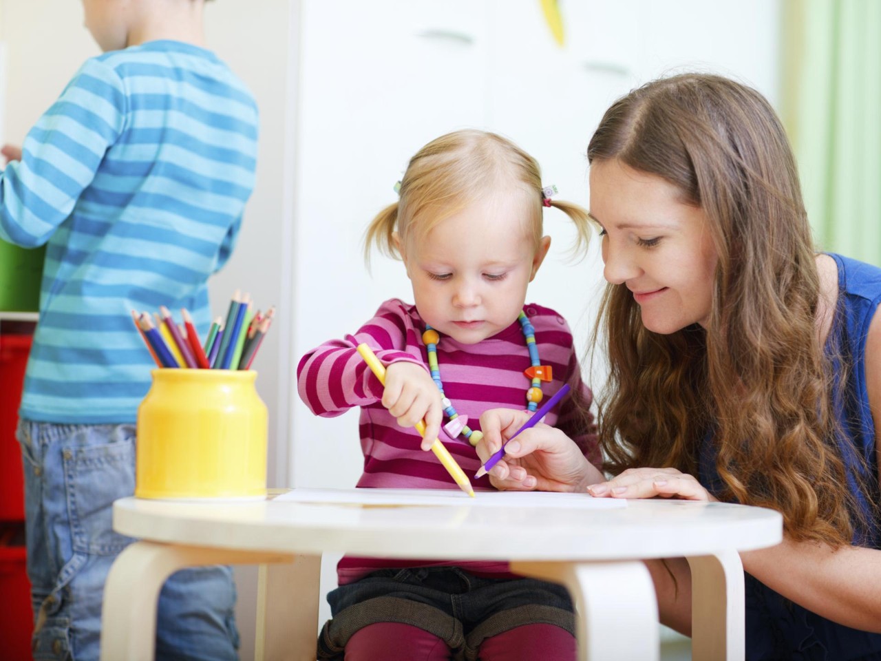 Lehrerin, die mit einem kleinen Mädchen zeichnet