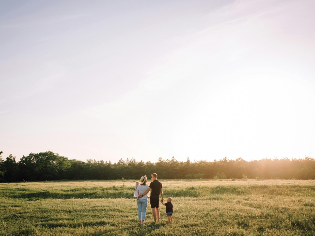 Eine Familie spaziert durch eine Wiese bei Sonnenuntergang