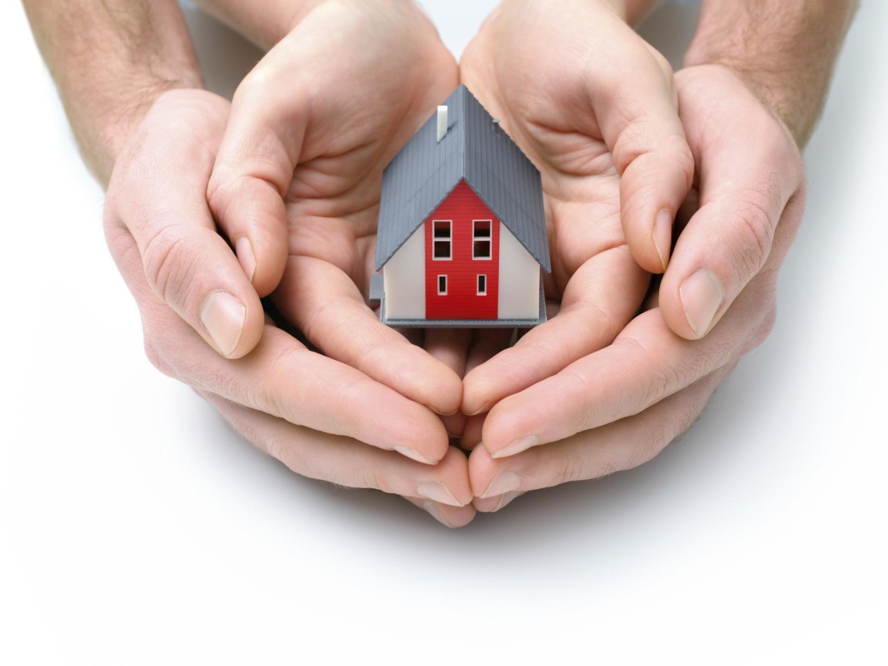 Zwei Handpaare, die ein Miniaturhaus halten