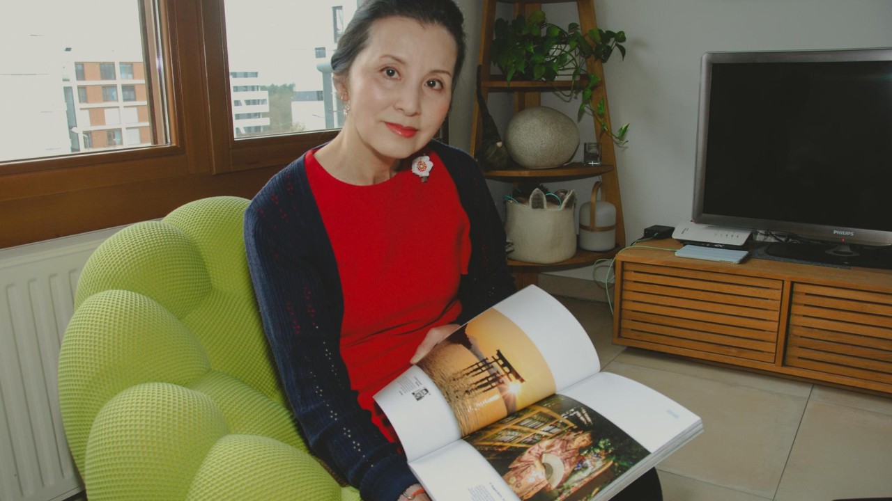 Harumi avec un livre sur le Japon dans en fauteuil dans son séjour.