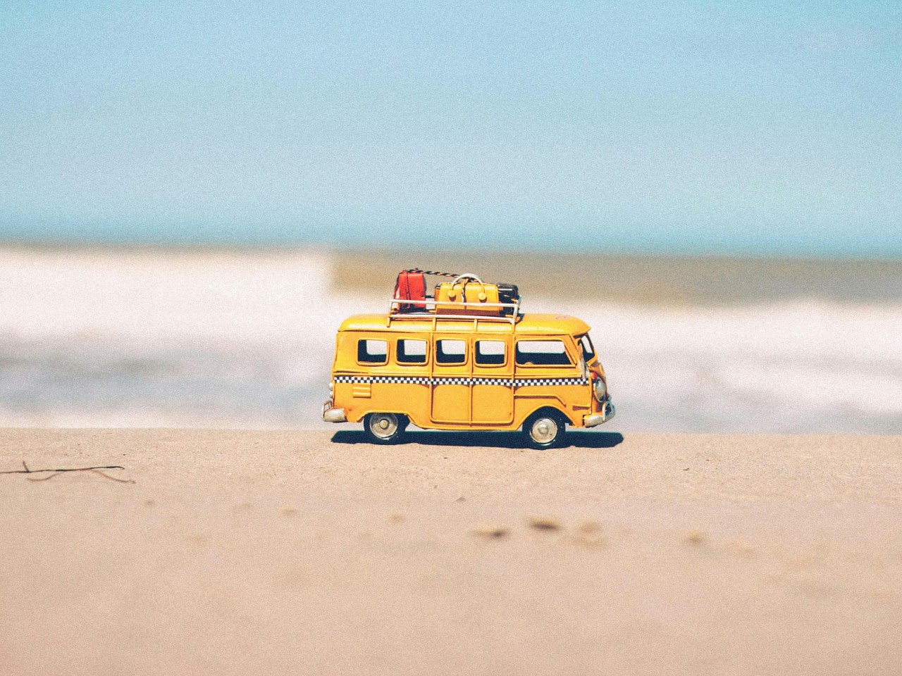 Un minibus jouet jaune sur la plage